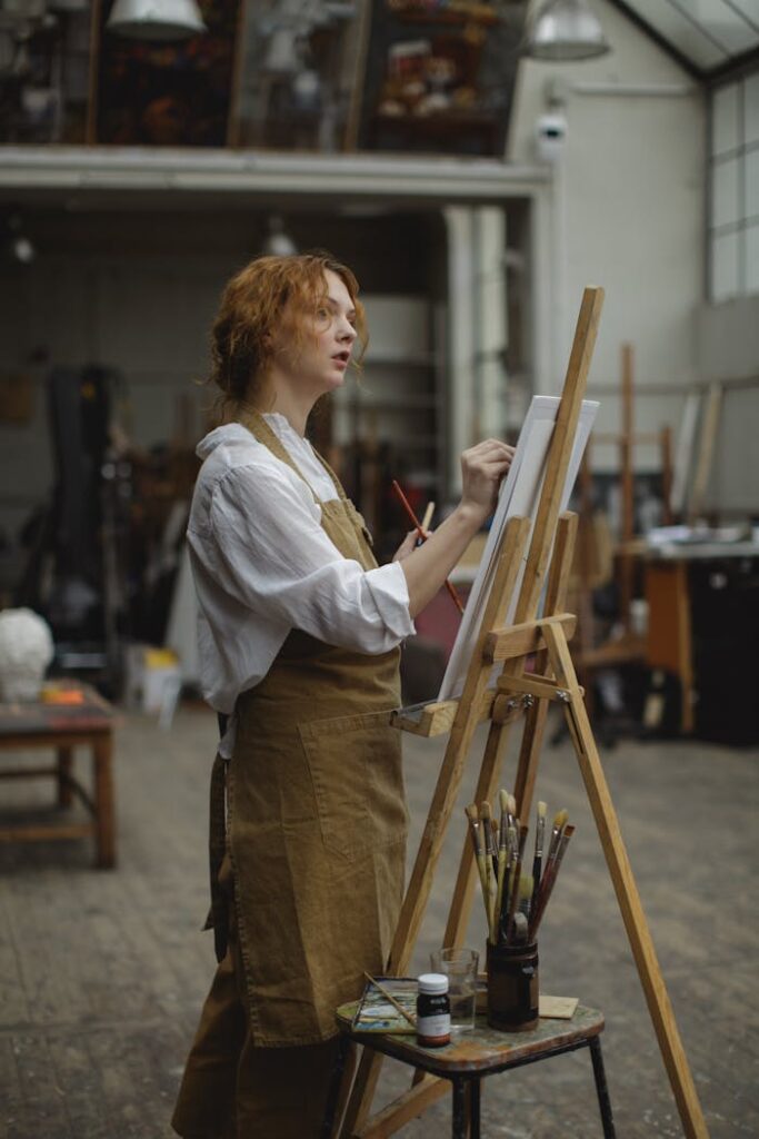 A focused female artist paints on canvas in an art studio, showcasing creativity and skill.