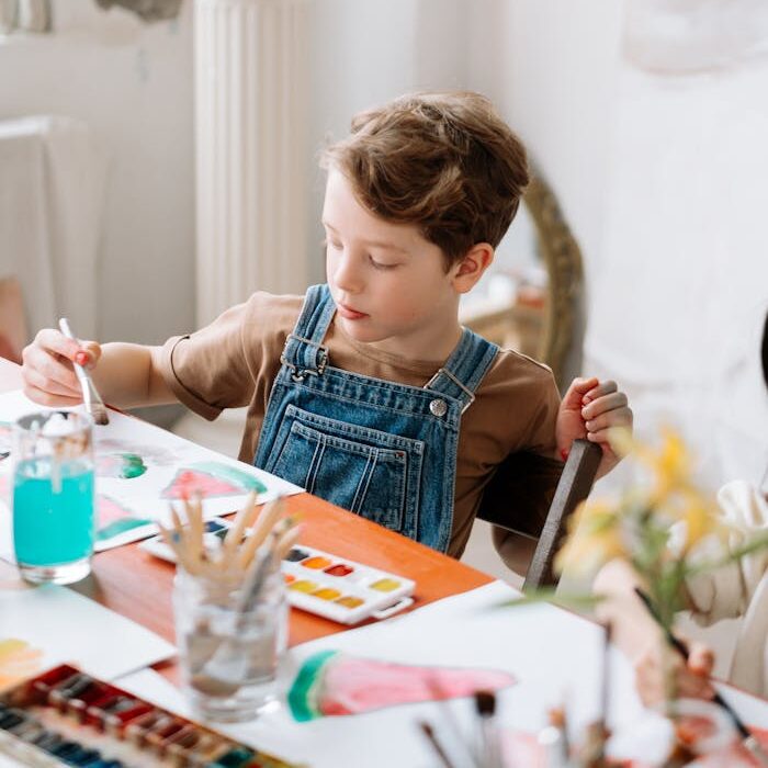 A young boy painting in a cozy art class setting, surrounded by art supplies and a welcoming atmosphere.