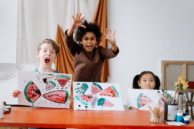 Joyful children displaying watermelon artwork in an interactive art class indoors.